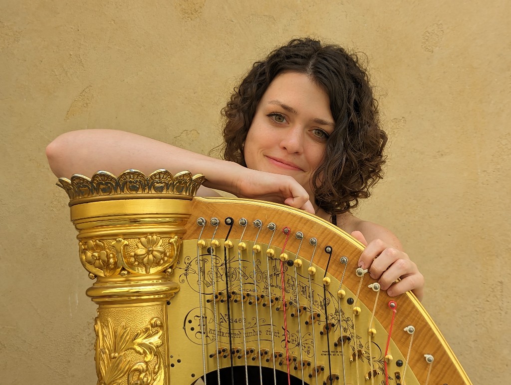 Kaitlin Miller leaning on a gold Lyon and Healy harp